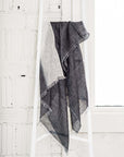 Granite Black White Ombre Linen Silk Handloom Scarf displayed elegantly on a white ladder against a textured wall.
