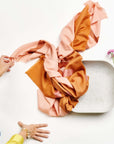 Canyon Hand Embroidered Hand Woven Merino Silk Soft Scarf displayed on a textured surface with pink flowers.