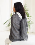 A woman wearing a Granite Black White Ombre Linen Silk Handloom Scarf, showcasing its elegant drape and texture.