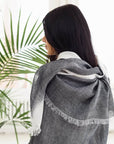 Person wearing a Granite Black White Ombre Linen Silk Handloom Scarf, showcasing its elegant design and texture.