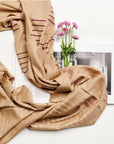 Maple Beige Handwoven Hand Embroidered Classic Scarf displayed with flowers and a book on a white background.