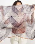 Samu Black hand crafted shibori print silk chiffon square scarf held up by a model, showcasing its elegant design.
