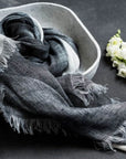 Granite Black White Ombre Linen Silk Handloom Scarf displayed in a bowl with a flower, showcasing its elegant texture and design.