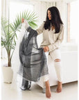 Model showcasing a Granite Black White Ombre Linen Silk Handloom Scarf in a bright, stylish setting with a green plant.