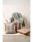 Oasis Charcoal Block Print Mulberry Silk Pillow Cover displayed on a chair with a stylish throw blanket.