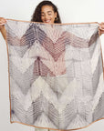Woman holding a Samu Black hand crafted chiffon square scarf with a shibori print design.