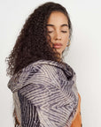 Chiffon square scarf Samu Black hand crafted shibori print silk worn elegantly by a woman with curly hair.
