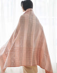 Silica Rose In Shades of Salmon Pink Gray Stripes Pattern Soft Handwoven Merino Throw draped over a model.
