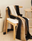 Siro Brown Handwoven Merino Artisan Throw Blanket draped over a wooden chair, showcasing its texture and design.