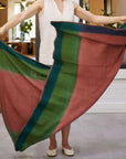 A person displaying the Still Garden Handwoven Throw in Hand Spun Merino in Dusty Pink Green Hues. Handwoven Brown Siro Soft Merino Throw Blanket.