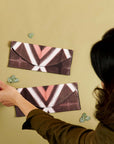 Tisa Artisanal Pouch In Black Pink Triangle Print displayed against a beige wall with hands adjusting the pouches.