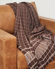 Treacle Checks Pattern Organic Cotton Handloom Throw draped over a brown armchair, showcasing its elegant design.