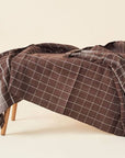 Treacle Checks Pattern Organic Cotton Handloom Throw draped elegantly on a wooden bench.