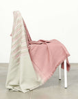 Chive Pink Green Ombre Handloom Merino Throw draped over a chair, showcasing its unique color and texture.