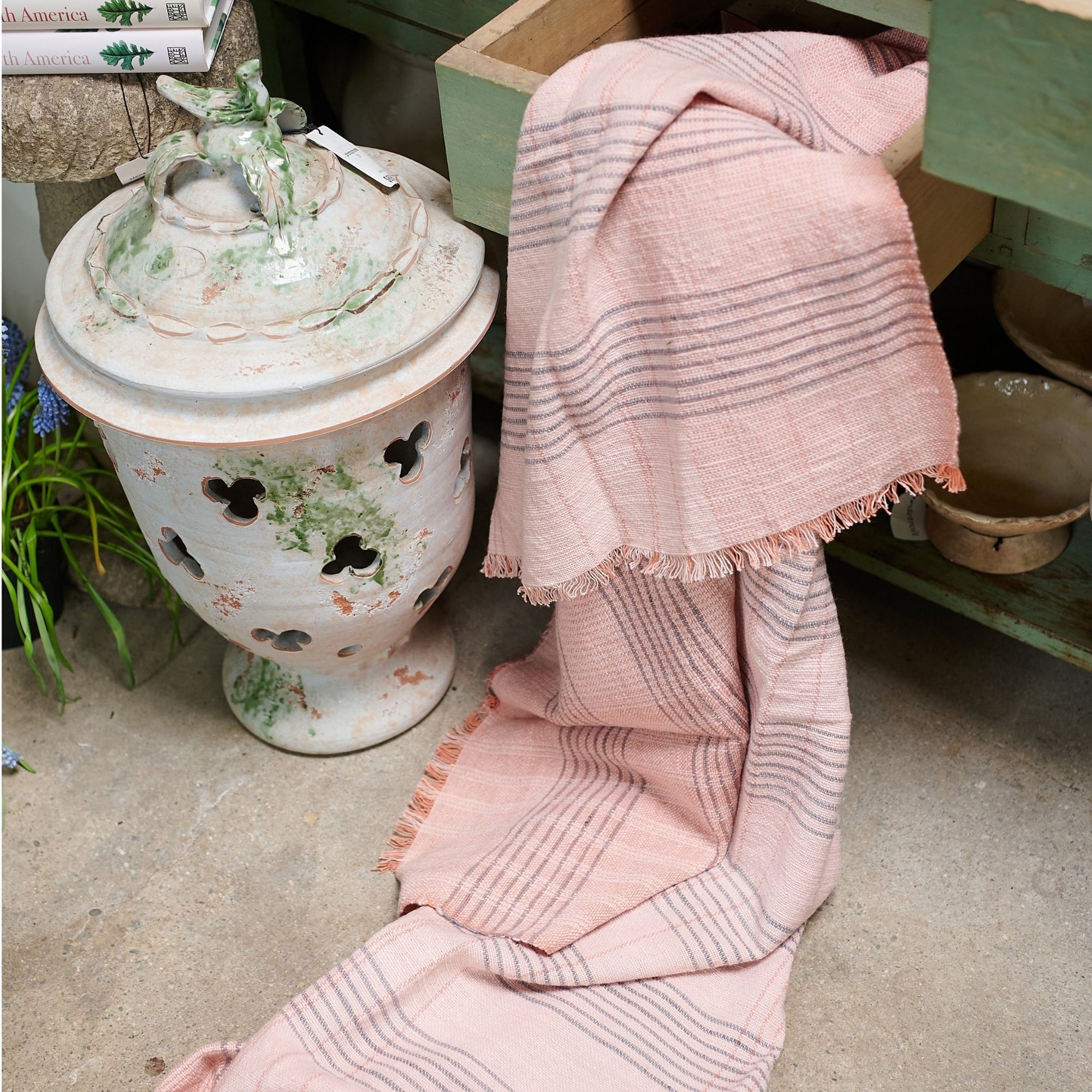 Silica Rose In Shades of Salmon Pink Gray Stripes Pattern Soft Handwoven Merino Throw displayed next to a decorative pot.