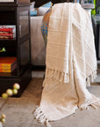 Sea Shell White Textured Checks Handloom Throw draped elegantly over a table in a modern living space.