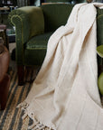Sea Shell White Textured Checks Handloom Throw draped over a green chair, showcasing its subtle texture and design.