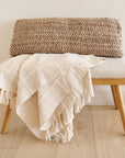 Sea Shell White Textured Checks Handloom Throw draped over a bench, showcasing its elegant texture and hand-rolled fringes.