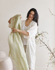Soya Pastel Lime Green Hand Woven Soft Linen Scarf being worn by a model in a minimalistic room.