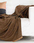 Hay Brown Twill Merino Handwoven Throw draped over a white sofa, showcasing its soft texture and rich color.
