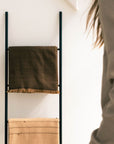 Hay Brown Twill Merino Handwoven Throw displayed on a wall ladder along with another blanket, showcasing its soft texture.