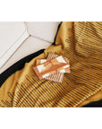 Handwoven Topaz Brown Myrtle Drift Merino Throw draped on a sofa with decorative items on top.