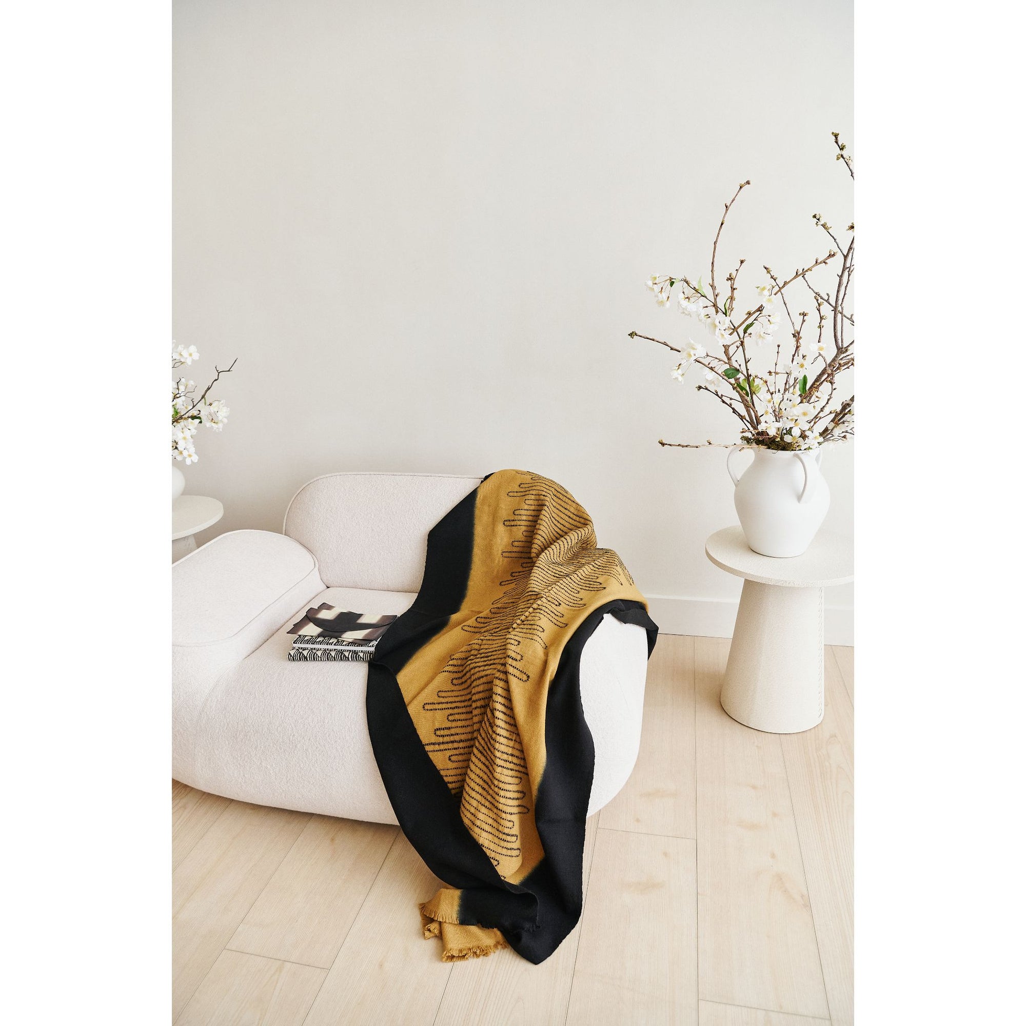 Handwoven Topaz Brown Myrtle Drift Merino Throw draped on a modern sofa, showcasing its artistic pattern and contrasting borders.