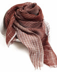 Auro Cinnabar Handwoven Earthy Rust Maroon Linen Scarf displayed elegantly in a bowl, showcasing its unique textures and patterns.