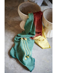 Avocado Green Multi Color Warm Hues Hand Woven Hand Knotted Textured Merino Throw draped over pots.