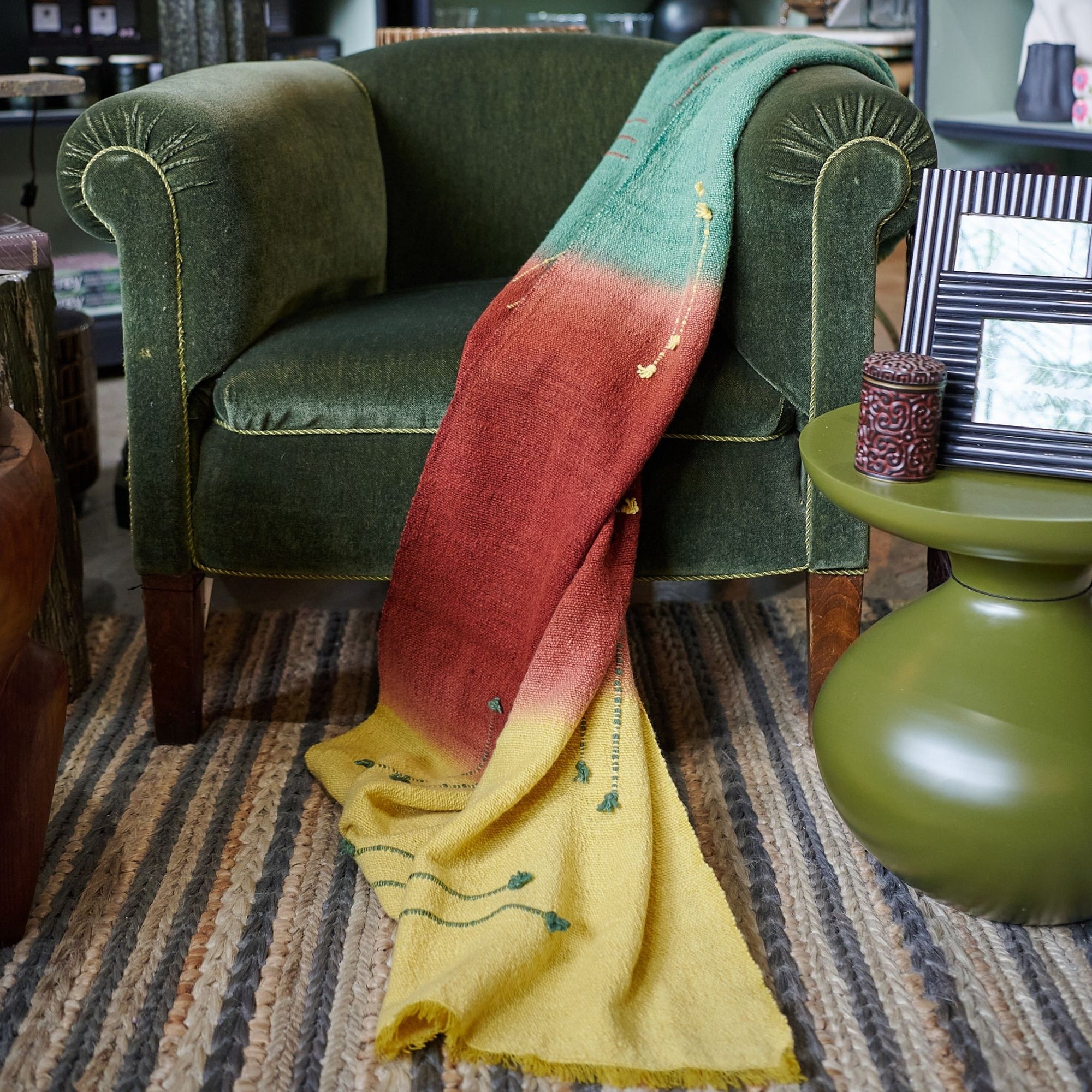 Avocado Green Multi Color Warm Hues Hand Woven Hand Knotted Textured Merino Throw draped over a green chair.