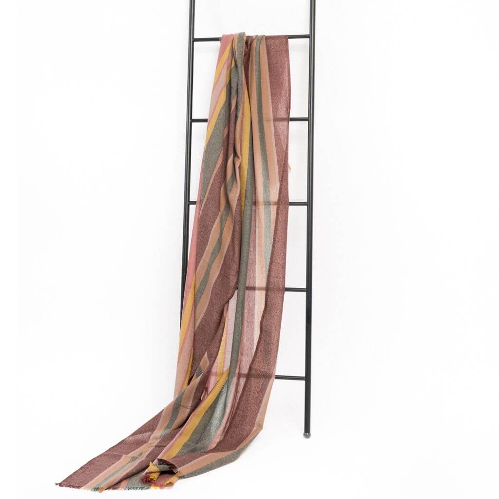 Barque Clay Modern Artisan Striped Soft Merino Handwoven Scarf displayed on a black ladder, showcasing its elegant colors.