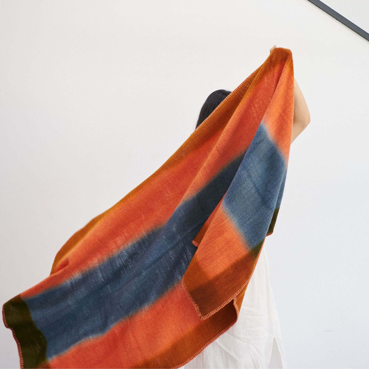 Ember Apricot In Orange and Blue Shades Handwoven Merino Throw Blanket displayed draped in vibrant colors.
