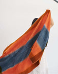 Ember Apricot In Orange and Blue Shades Handwoven Merino Throw Blanket displayed draped in vibrant colors.
