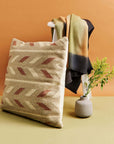 Ero Green Brown Geometric Pattern Hand Woven Large Pillow displayed with a blanket and vase on a stool.
