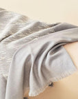Flo Gray Textured Handloom Merino Throw draped elegantly over a chair, showcasing its luxurious texture and craftsmanship.