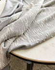 Flo Gray Textured Handloom Merino Throw draped elegantly on a marble table, showcasing its luxurious design and craftsmanship.