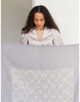 Woman showcasing the Flo Gray Textured Handloom Merino Throw with intricate designs and luxurious texture.