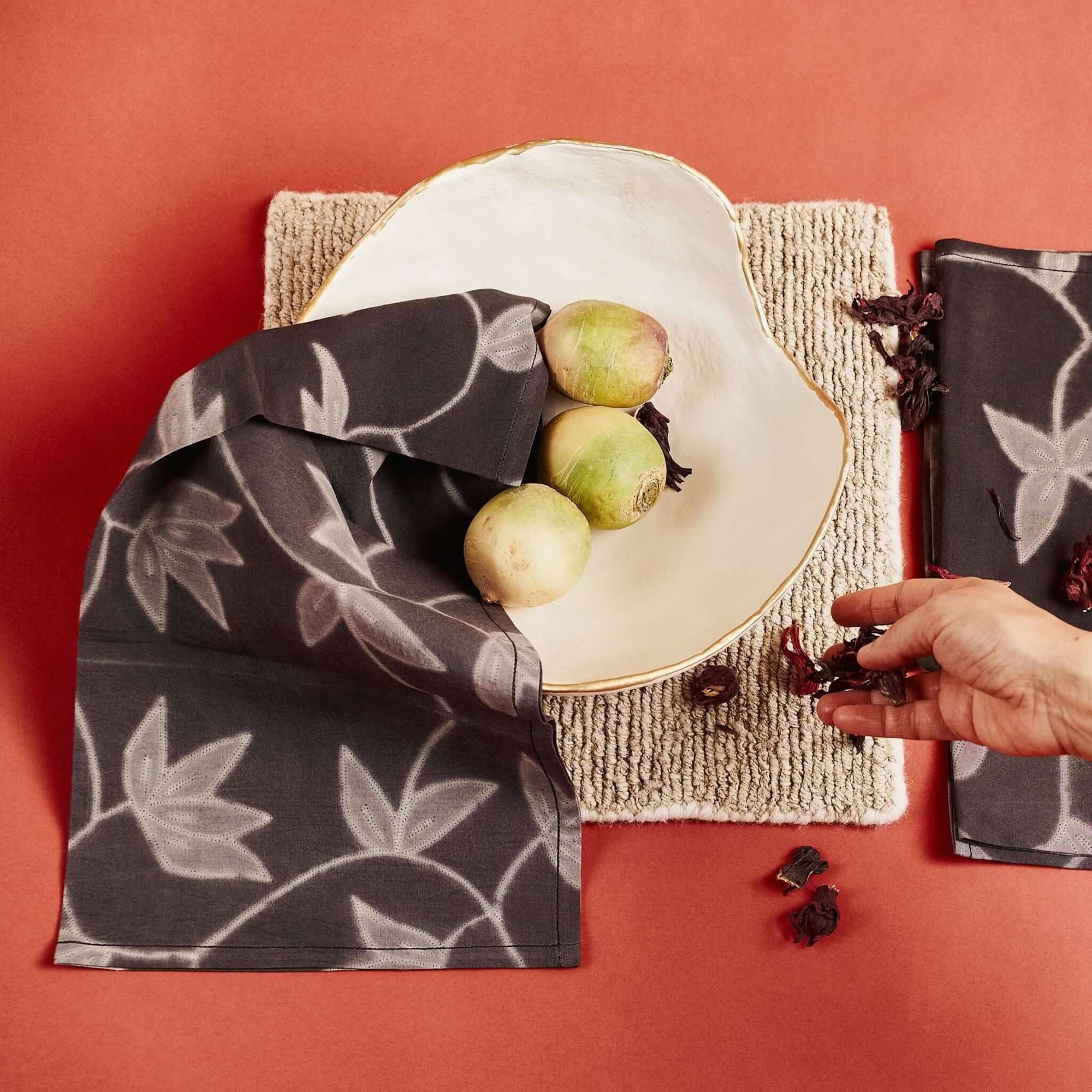 Folio Black Handcrafted Shibori Print Cotton Table Napkins ( set of 4 ) displayed with a bowl and fruit on a textured surface.