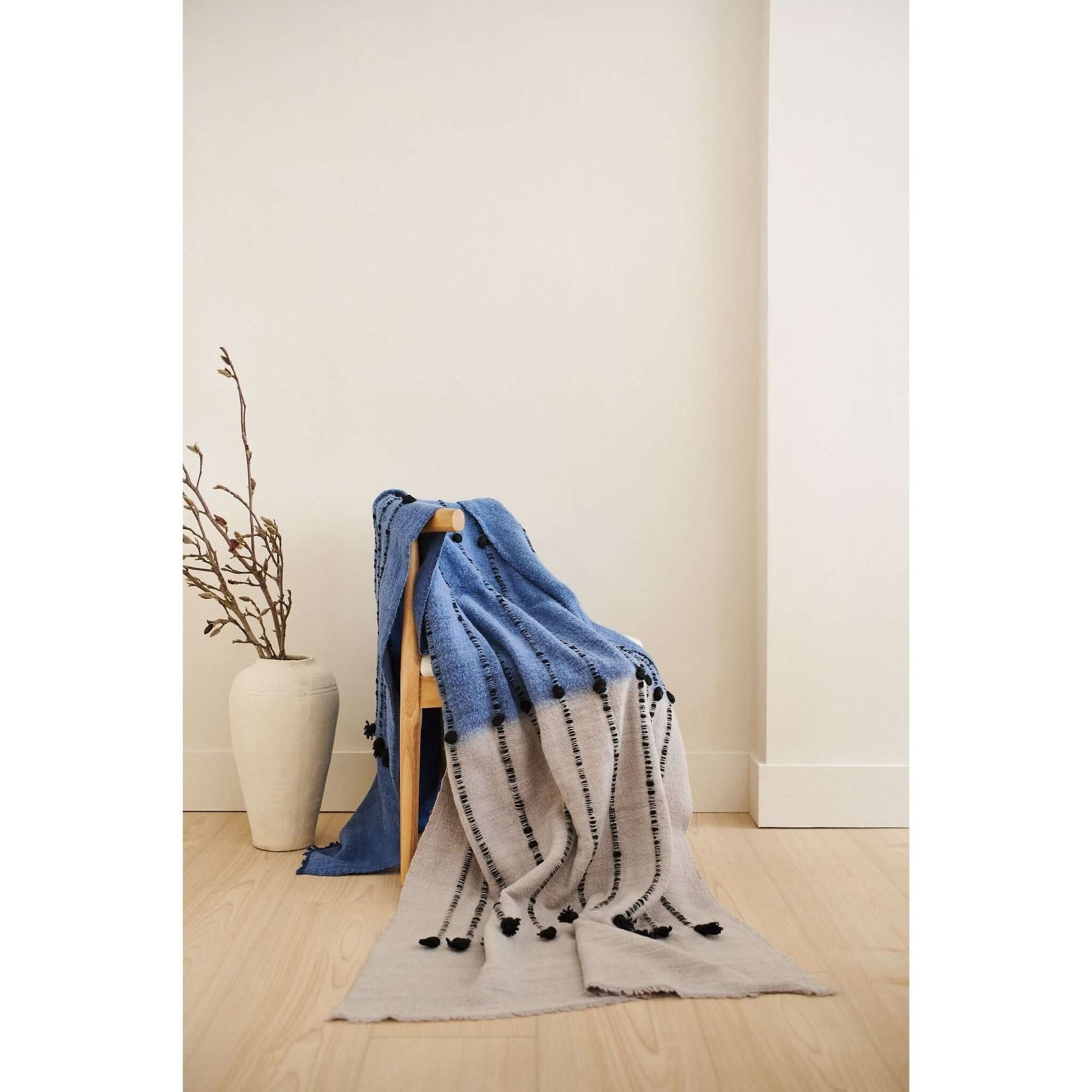 Hand Knotted Merino Textured Mari Throw Blanket in Blue Gray draped elegantly over a chair, highlighting its unique textures.