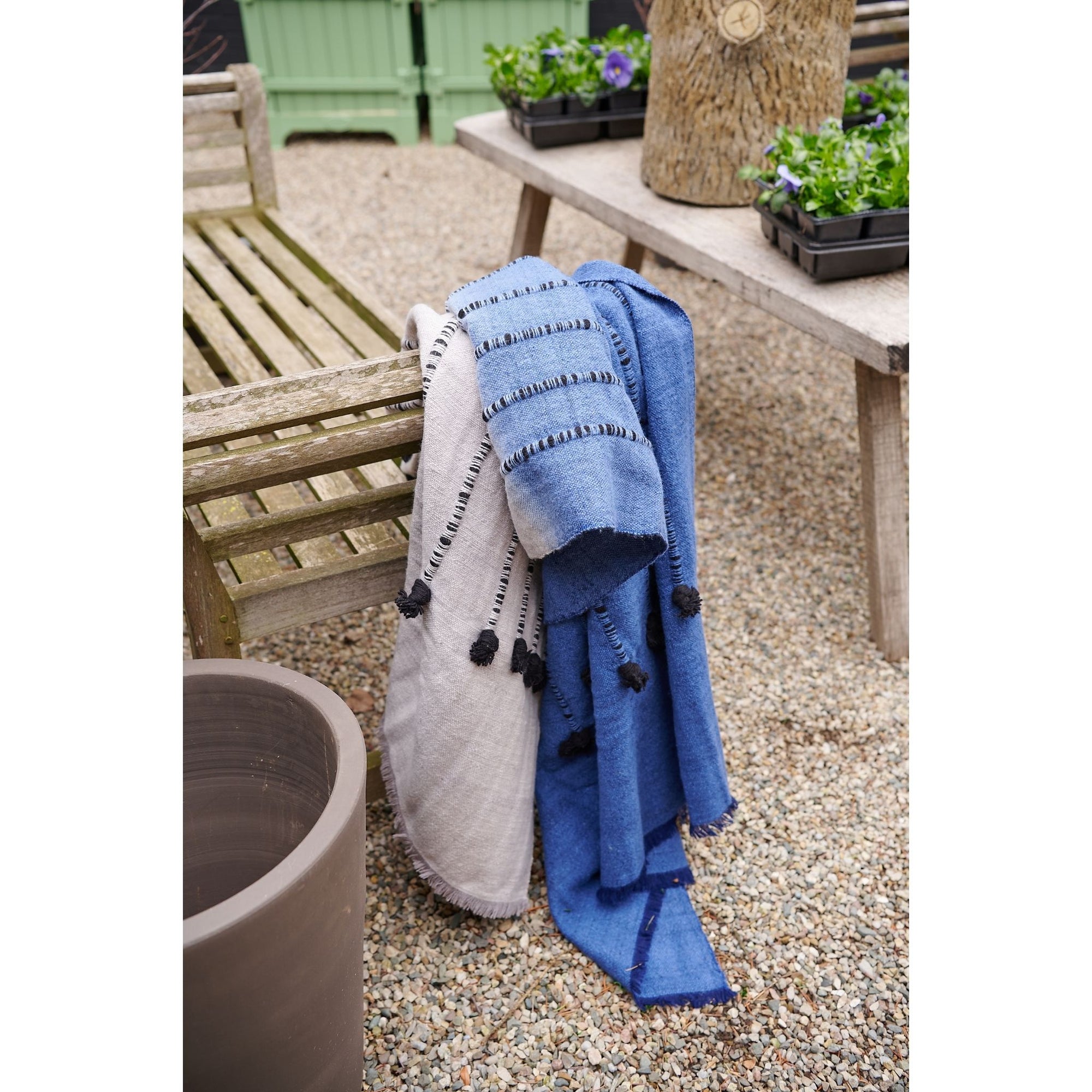 Hand Knotted Merino Textured Mari Throw Blanket in Blue Gray draped elegantly over outdoor furniture.