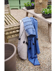Hand Knotted Merino Textured Mari Throw Blanket in Blue Gray draped elegantly over outdoor furniture.
