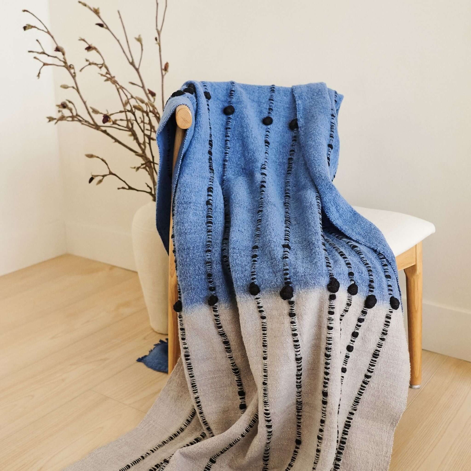 Hand Knotted Merino Textured Mari Throw Blanket in Blue Gray draped on a chair, showcasing its unique texture and design.
