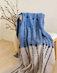 Hand Knotted Merino Textured Mari Throw Blanket in Blue Gray draped on a chair, showcasing its unique texture and design.
