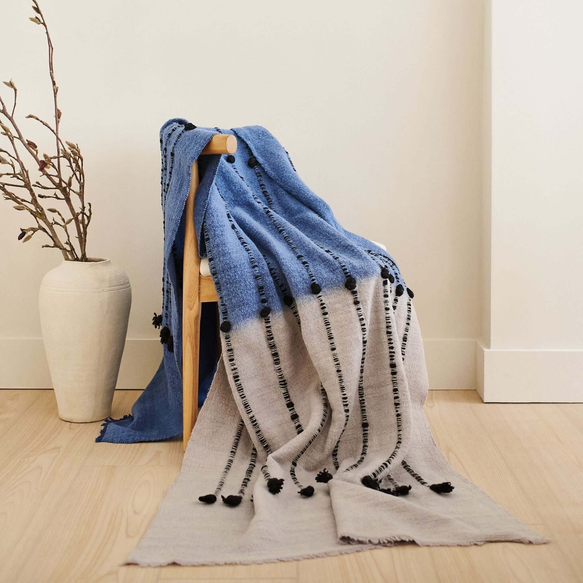 Hand Knotted Merino Textured Mari Throw Blanket in Blue Gray draped over a chair with a minimalist decor backdrop.