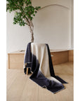 Ink Black White Ombre Textured Throw In Hand Spun Merino And Hand Stitched Hem draped on a chair in a bright room.