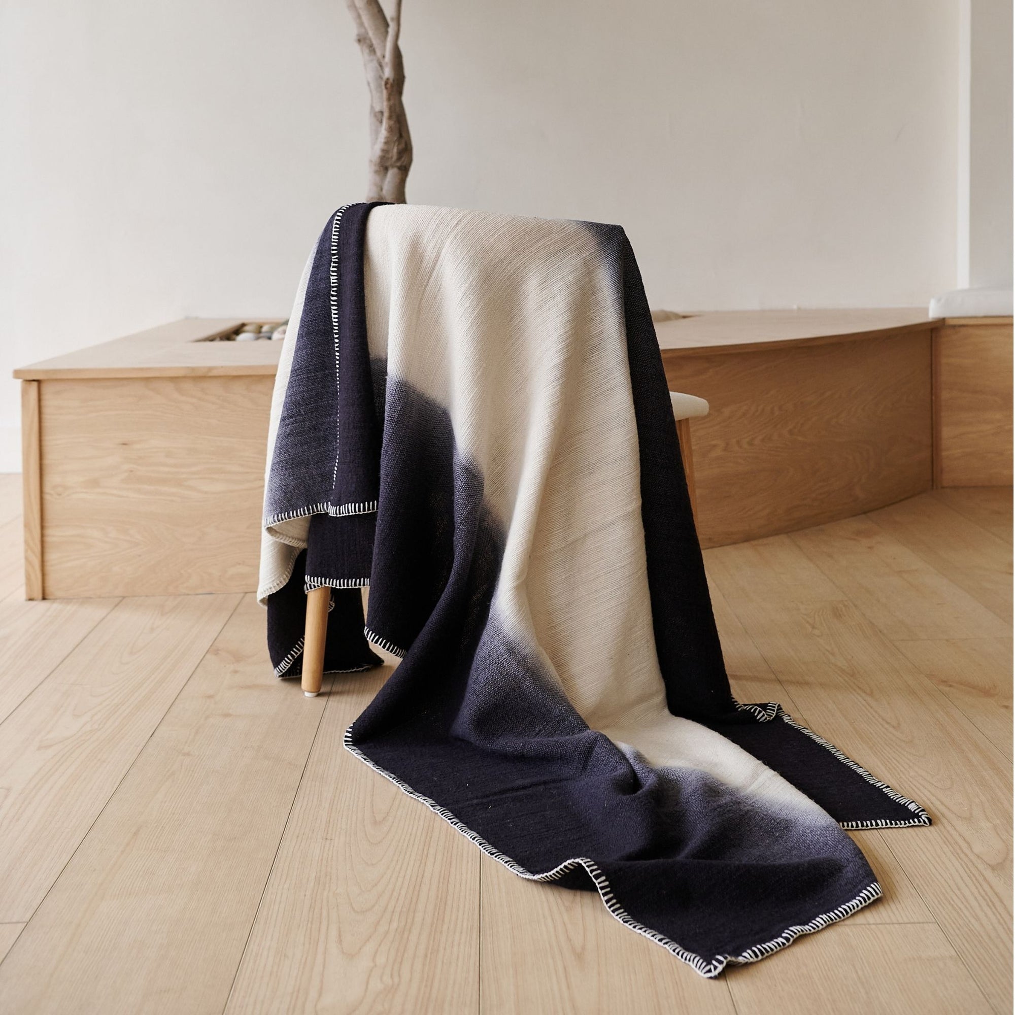 Ink Black White Ombre Textured Throw  In Hand Spun Merino And Hand Stitched Hem draped over a chair.