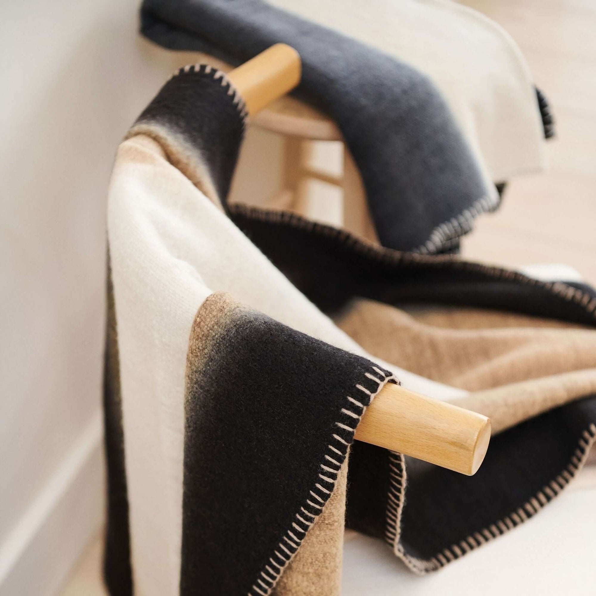 Ink Black White Ombre Textured Throw  In Hand Spun Merino And Hand Stitched Hem draping over a wooden chair