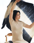 Woman joyfully displaying the Ink Black White Ombre Textured Throw In Hand Spun Merino And Hand Stitched Hem.