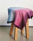 Iris Haze Blue Pink Cashmere Merino Handloom Scarf displayed on a wooden stool with soft color gradients.