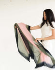 Model holding Iris Kiwi Green Pink Cashmere Merino Handwoven Scarf showcasing its unique colors and craftsmanship.